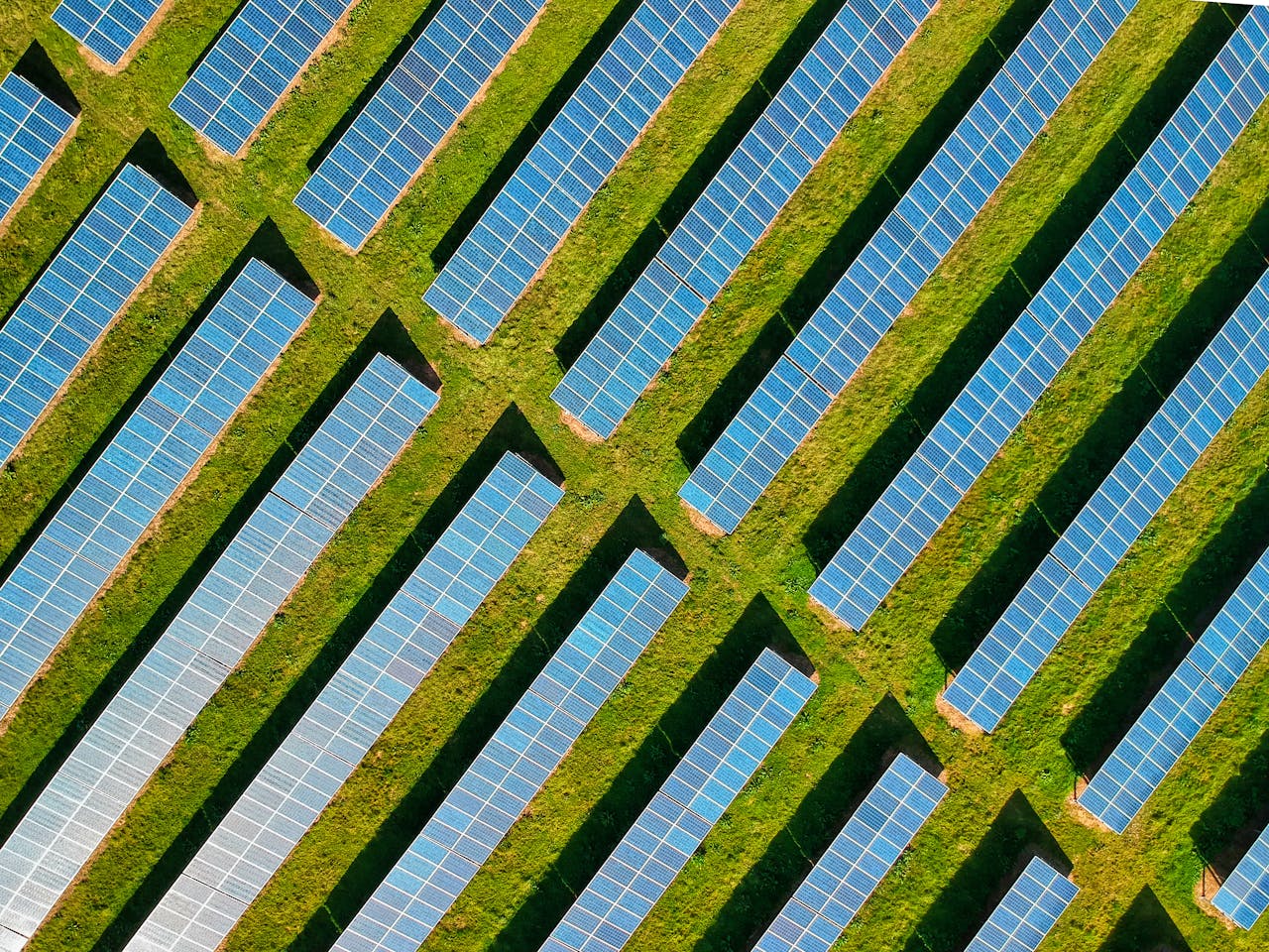 About High-angle aerial shot of solar panels in a lush green field, located in Rockbeare, UK.
